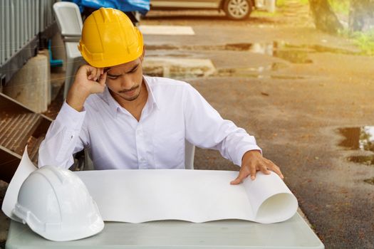 Young Asia man engineer wearing safety yellow helmet in white shirt checking construction site building.