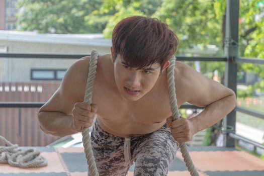 Asian young man is exercising by pulling a rope.