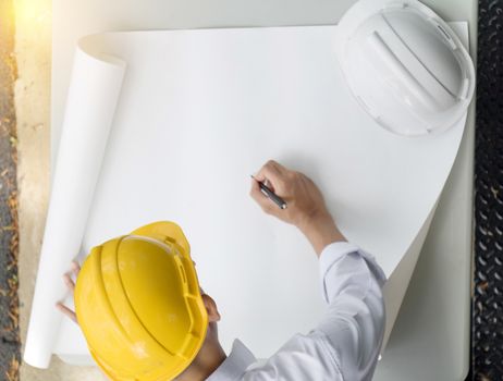 Young Asia man engineer wearing safety yellow helmet in white shirt checking construction site building.