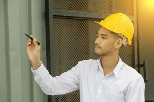 Young Asia man engineer wearing safety yellow helmet in white shirt checking construction site building.