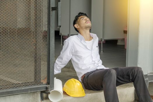 Young Asian engineers wear white shirts are stressed with yellow safety helmets and planks.