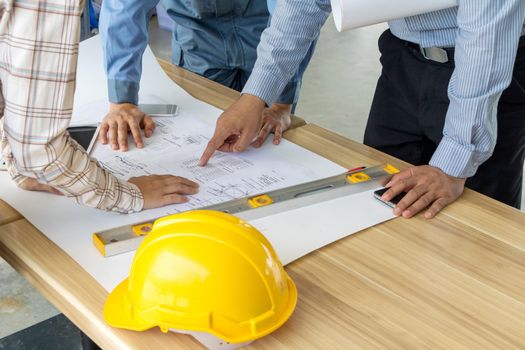 A group of engineers are looking at a blueprint for construction on the table. Engineering concept.