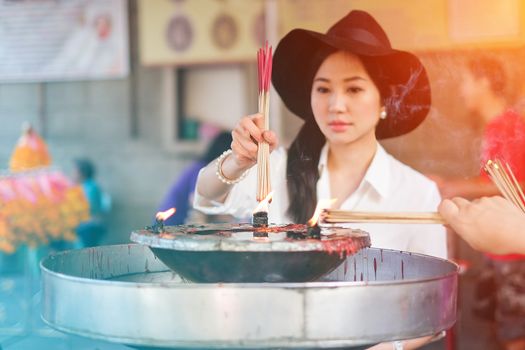 Woman holding burning incense sticks in chinese temple