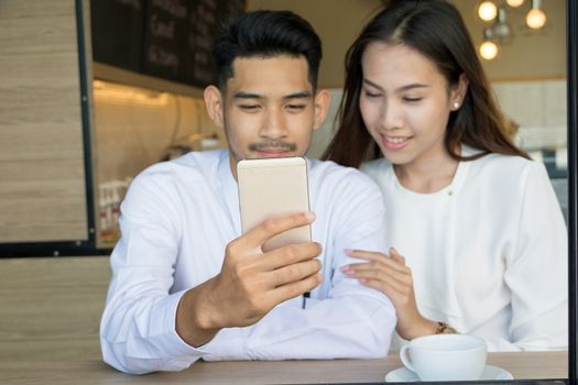 Asian young couple in love at a coffee shop, they are smile. Conception in coffee shop.