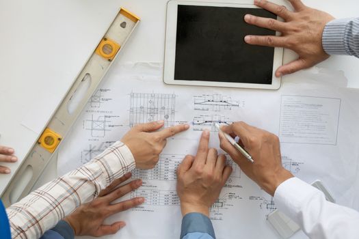 A group of engineers are looking at a blueprint for construction on the table. Engineering concept.