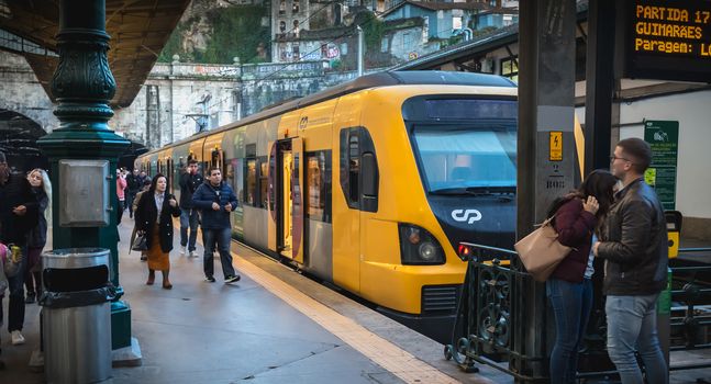 Porto, Portugal - November 30, 2018: Interior of Porto Sao Bento train station where people walk on the dock near the train stationary on a winter day