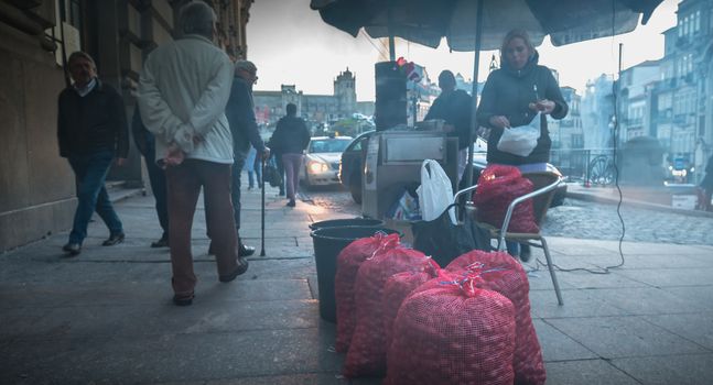 Porto, Portugal - 30 November 2018: Street vendors of roasted chestnuts in front of Sao Bento station in the city center on a fall day