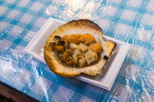 The roasted scallops seasoning with garnish japanese style at put on the table in Kuromon Ichiba market. Japan.