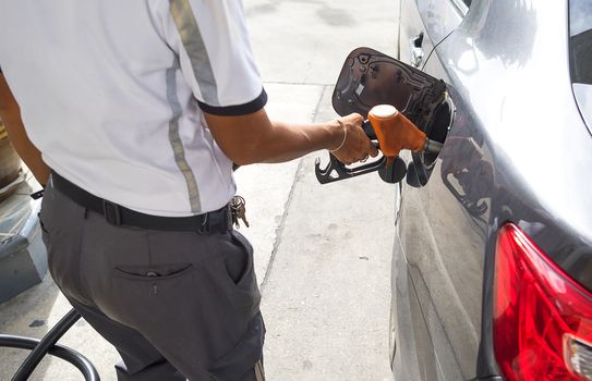 man pumping gasoline fuel in car at gas station