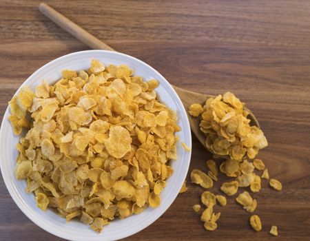 Corn flakes and bowl on wood table