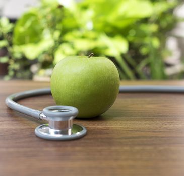 Green apple with stethoscope for health concept