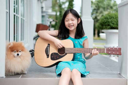 Asian Child Playing Guitar with Dog