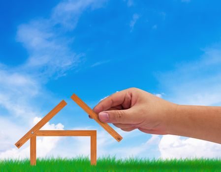 Building new house, home concept, hand holding wood plank on blue sky background