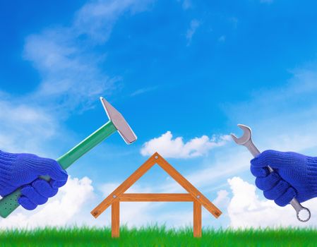 Building new house, home concept, hand holding tools on blue sky background