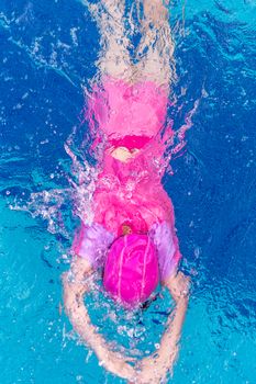 Child or kid swimming in swimming pool from top view.