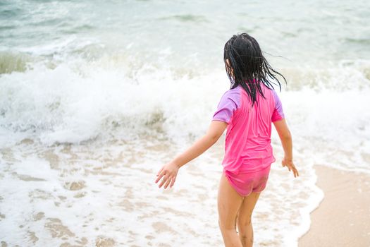 Rear View of Asian Child on Sea Beach with Ocean Wave