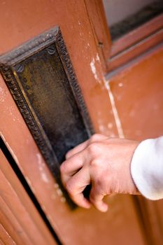 Close-up shot of hand holding door knob opening a wooden door.