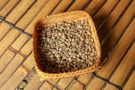 Wicker robe made of bamboo strips filled with fresh Arabica coffee beans. Close up of natural process of coffee beans drying on coffee factory in Bali. Dried coffee beans ready for roasting process.