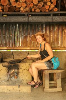Young woman roasting coffee beans in a cast iron pan. Using traditional methods at a coffee plantation farm in Bali, Indonesia, Asia. Coffee making process by roasting beans. Over a wood fire stove.