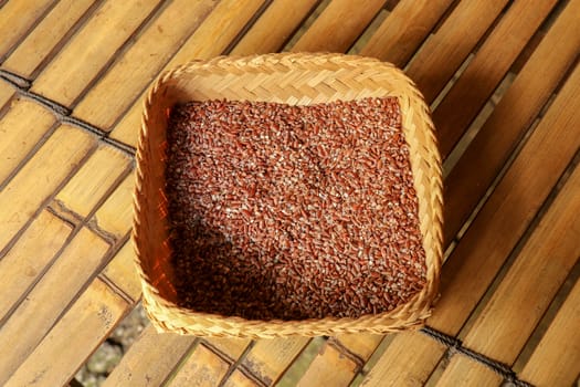 Wicker robe made of bamboo strips filled with fresh natural organic rice. Close up of natural process of rice drying on factory in Bali. Dried rice seeds.