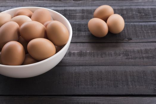 Chicken egg in white bowl and 3 chicken egg out side on Black color wood table