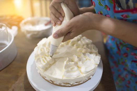 Women hand decorating with a pastry bag with cream