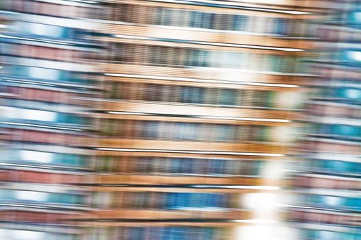 A blue and orange abstract photographic view of buildings in movement in the city, with a grain reticulation texture effect