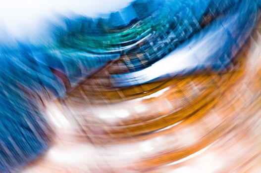 A blue and orange abstract photographic view of buildings in movement in the city, with a grain reticulation texture effect