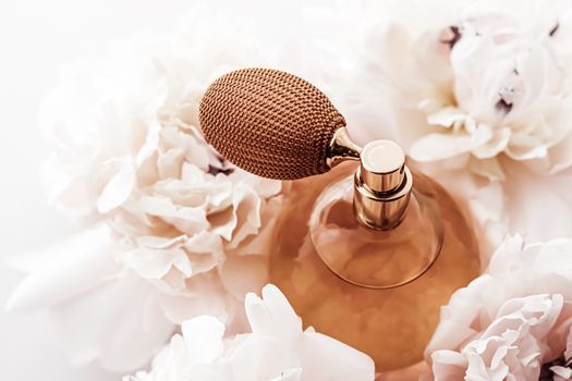 Fragrance bottle as vintage perfume product on background of peony flowers, parfum ad and beauty branding design