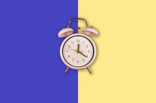 ringing twin bell vintage classic alarm clock Isolated on phantom blue and yellow pastel colorful trendy background. Copy space abailable