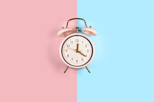 Ringing twin bell vintage classic alarm clock Isolated on blue and pink pastel colorful trendy background. Copy space abailable