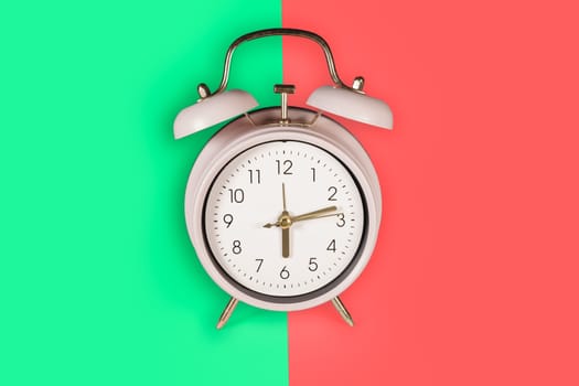 Ringing twin bell vintage classic alarm clock Isolated on red and green pastel colorful trendy background. Copy space available
