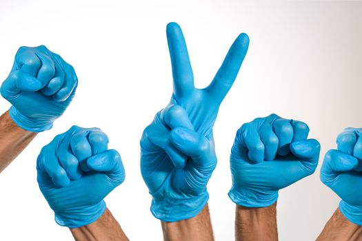 Medical hands with blue gloves, one of them doing the Victory gesture, symbolizing the fight and victory over diseases such as COVID-19 by coronavirus