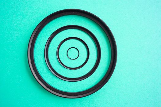 Concentric camera Lens Filter Up and Down Ring Adapters on a teal background