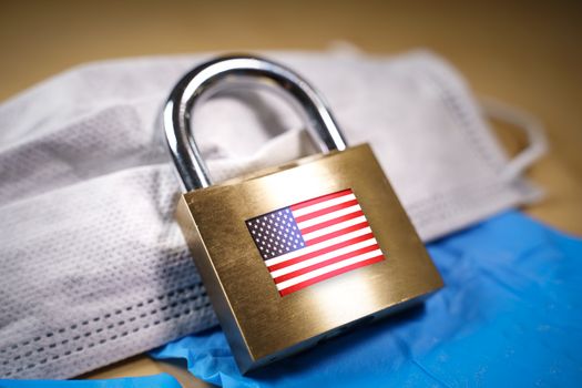 Closed padlock with the USA flag over a face mask. Coronavirus or covid-19 quarantine and national lockdown concept
