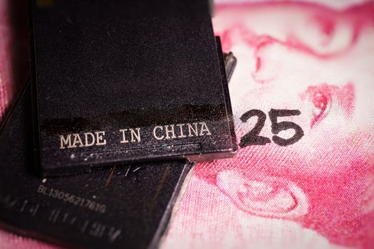 Made in china text written on a piece of plastic over a yuan bill with the number 25 on it. Concept of Made in China 2025, a blueprint to upgrade the manufacturing capabilities of Chinese industries into a more technology-intensive powerhouse
