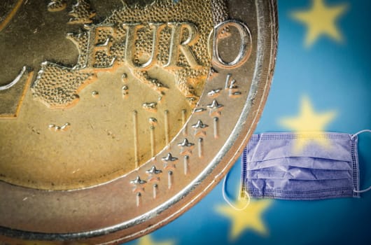 2 Euro coin with a face surgical mask. on the background. Concept for high price of surgical masks, economic crisis and coronavirus fight during the COVID-19 epidemic in Europe.