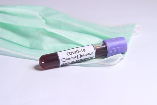 Simple Conceptual, Glass Blood Covid-19 Test tube, above N95 Surgical Mask