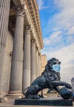 Bronze lion statue in front of the Spanish Parliament wearing a face mask as a symbol of the Madrid and Spain lockdown caused by coronavirus outbreak..