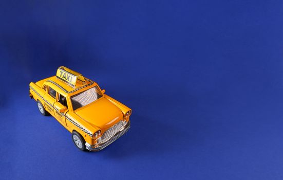 Model of yellow retro New York city taxi cab against a blue background. Complementary colors and copy space available