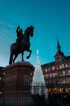 Madrid, bronze statue of King Philip III and illuminated christmas tree in Plaza Mayor.