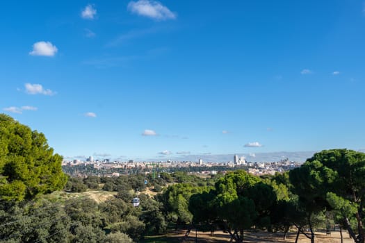 Cable car over casa de campo park and Madrid skyline on the Background.