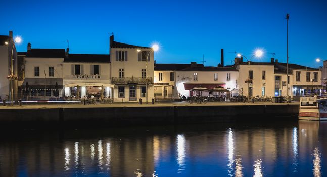 Port Joinville, France - September 19, 2018: view of the main port of the Yeu island with its picturesque architecture and its fishing boats at night on a fall day