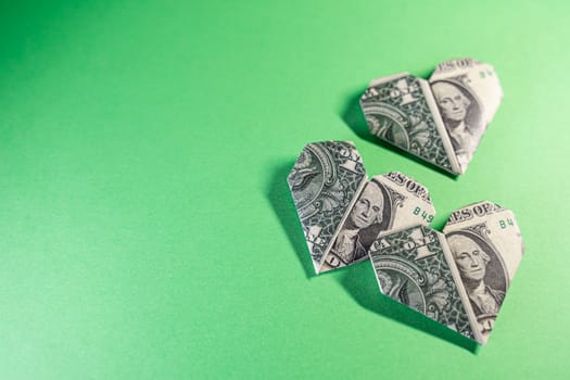 One Dollar origami hearts on a paper background. Paper craft, suitable for greed, business, richness or money love concepts with available copy space.