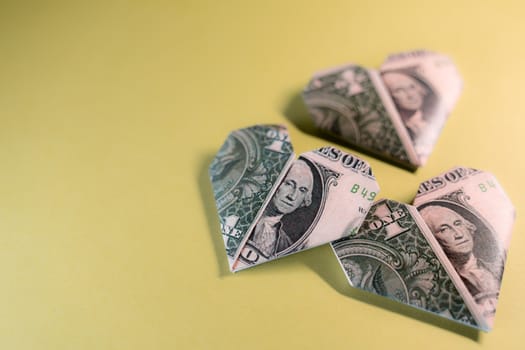 One Dollar origami hearts on a paper background. Paper craft, suitable for greed, business, richness or money love concepts with available copy space.