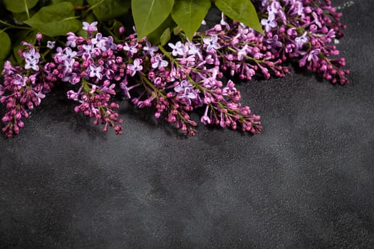 Purple lilac flowers bouquet on black concrete background. Stylish floral greeting card. Happy mothers day.