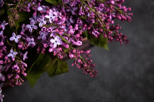 Purple lilac flowers bouquet on black concrete background. Stylish floral greeting card. Happy mothers day.