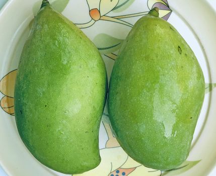 Beautiful view of green mango fruit kept in a plate for sale during the summer season