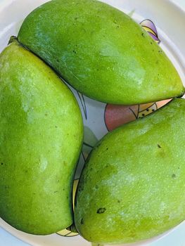 Beautiful view of green mango fruit kept in a plate for sale during the summer season