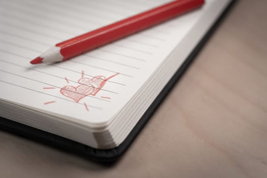 love hearts on notebook with red pen over a wooden table. Suitable for love, valentine, anniversary, couple and friendship concepts.